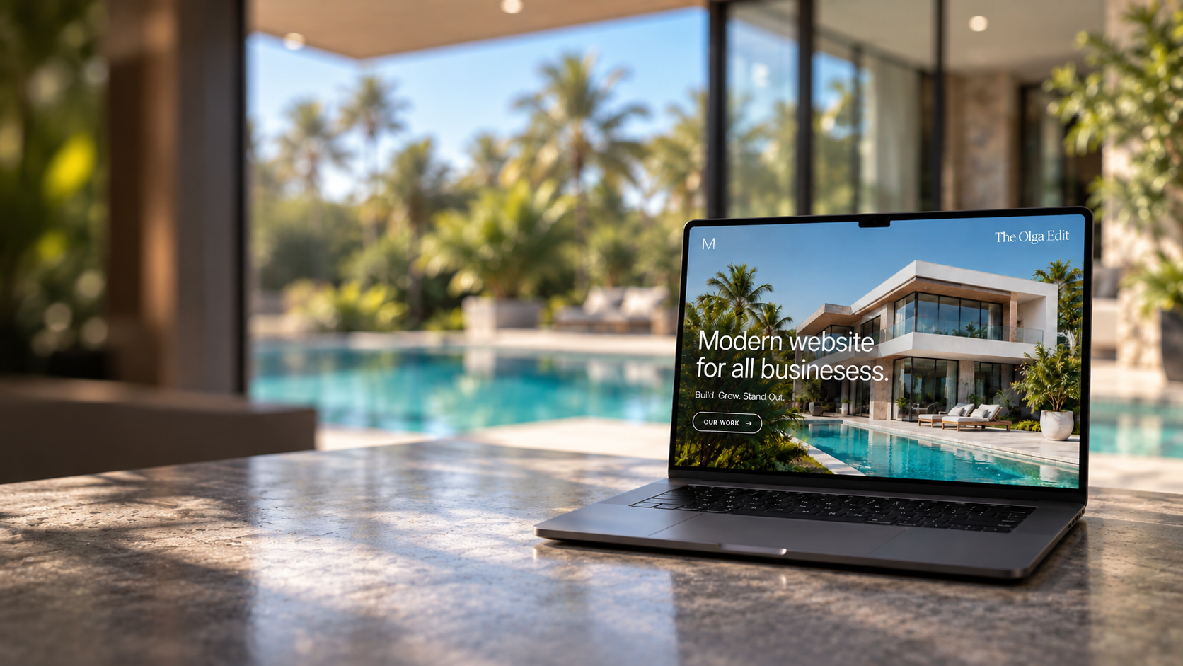 Laptop showing The Olga Edit website beside a tropical villa pool